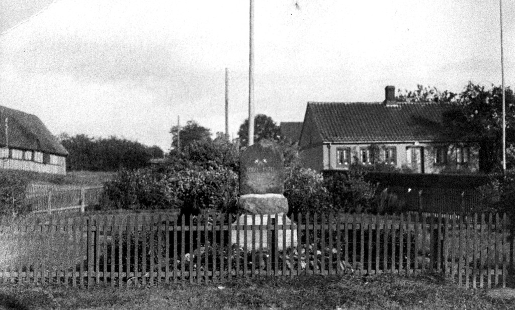 1939. Omkring mindestenen står et lille anlæg indrammet af stakit. Alt ånder fred og idyl.