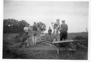 Her er man gået i gang med at grave ud til kælder til det nye hus på Bysvinget 11 i 1960. Alt skete med håndkraft. Personerne er f.v. far Niels Henning, morbror Torben Olsen, Bent Christensen, Birgit på skuldrene af Jette Christensen og bedstefar Jens Henrik Olsen. I baggrunden ses Borumgård, Langelinie 59